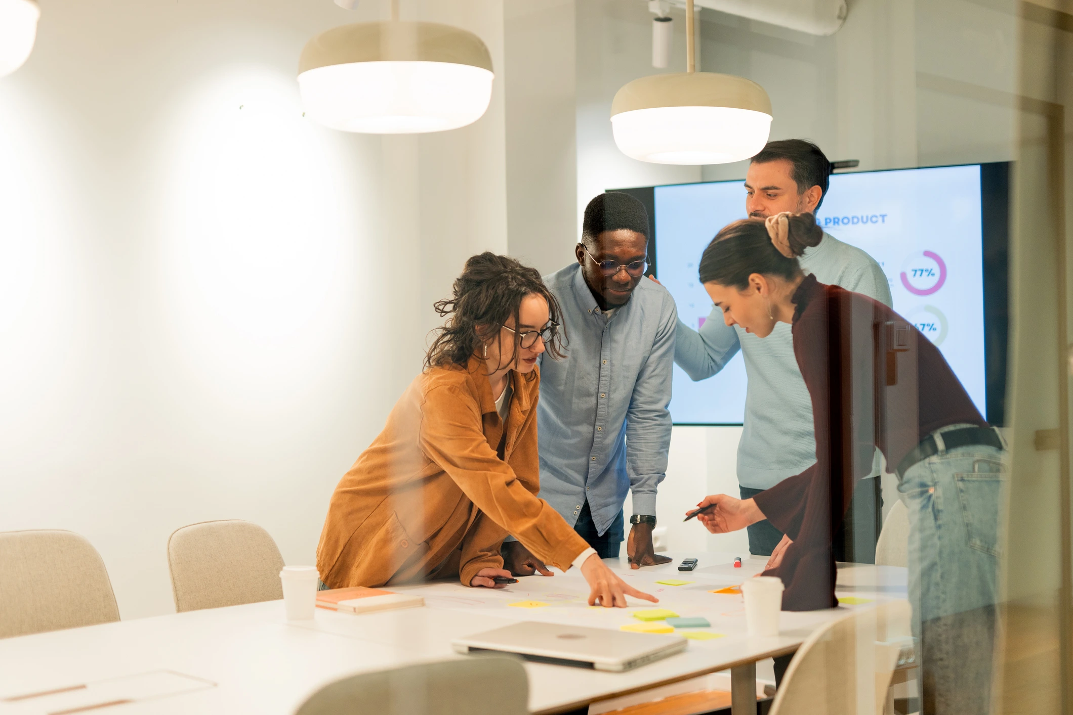 Team of people stood in front of a large screen around a table planning their business