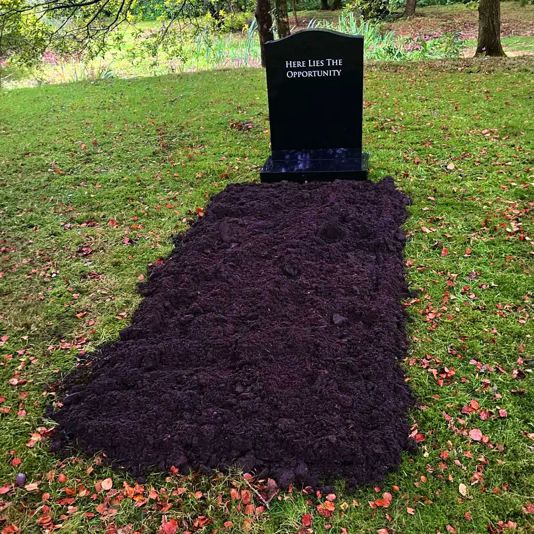 Freshly dug grave with a headstone reading “Here Lies The Opportunity